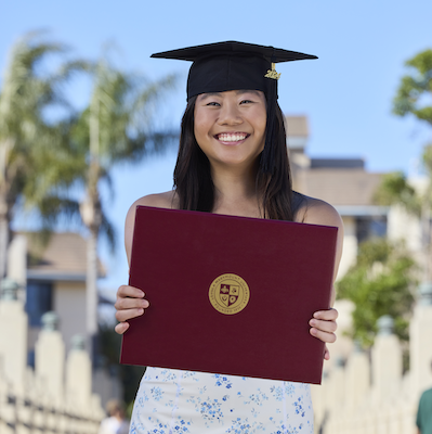 Iliana Chen outside holding diploma